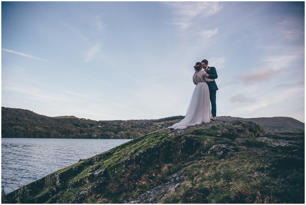 Bride and groom stand on hill peak at the Lake District