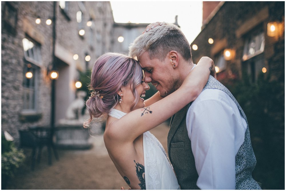 Tattooed bride and groom hug at Holmes Mill wedding venue in Clitheroe
