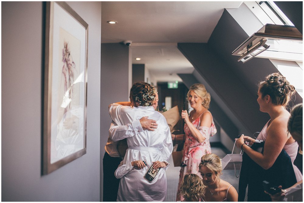 Bride gets hugged by her pageboy and her dad before her wedding