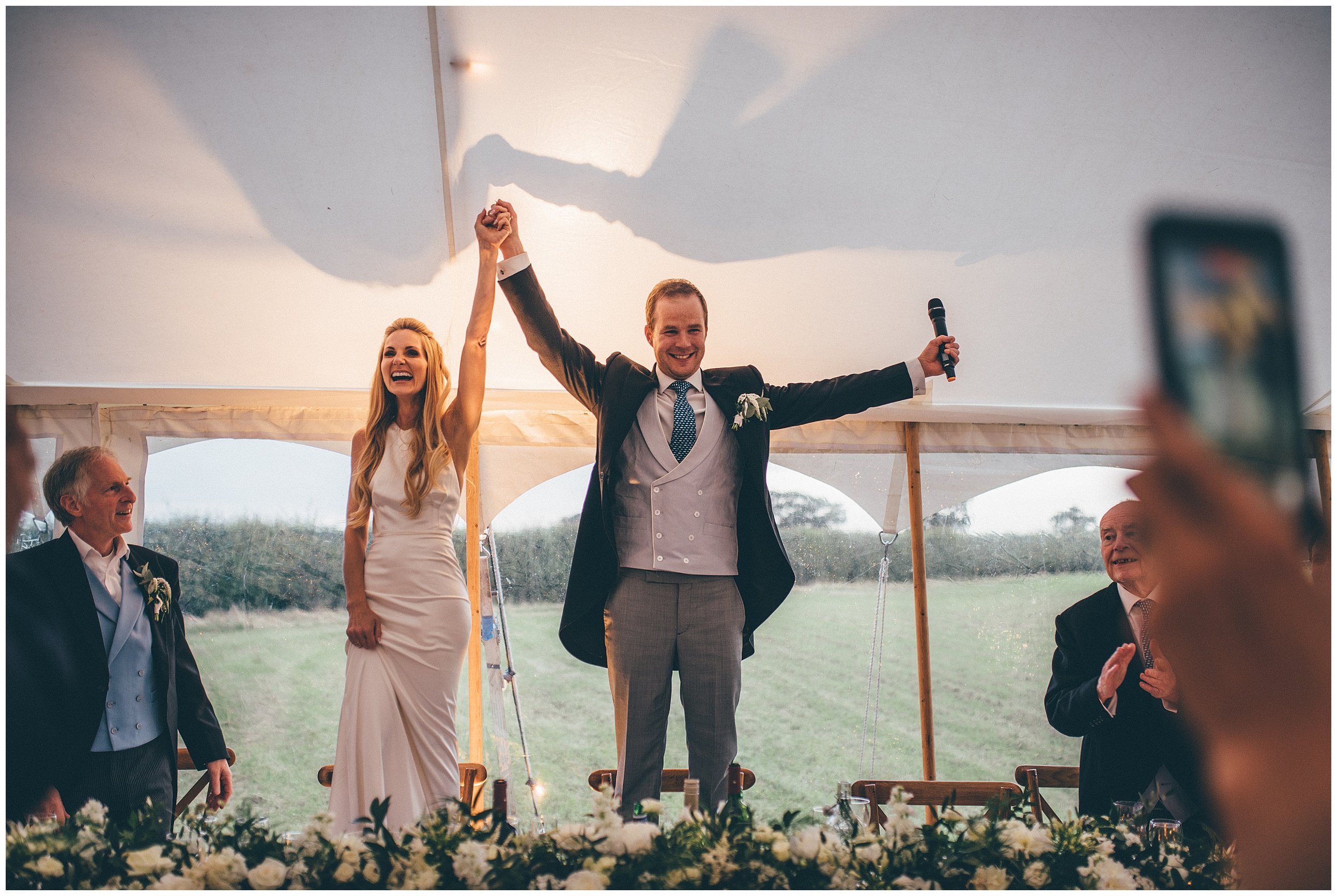 Bride and groom stand on chairs celebrating at their Cheshire wedding