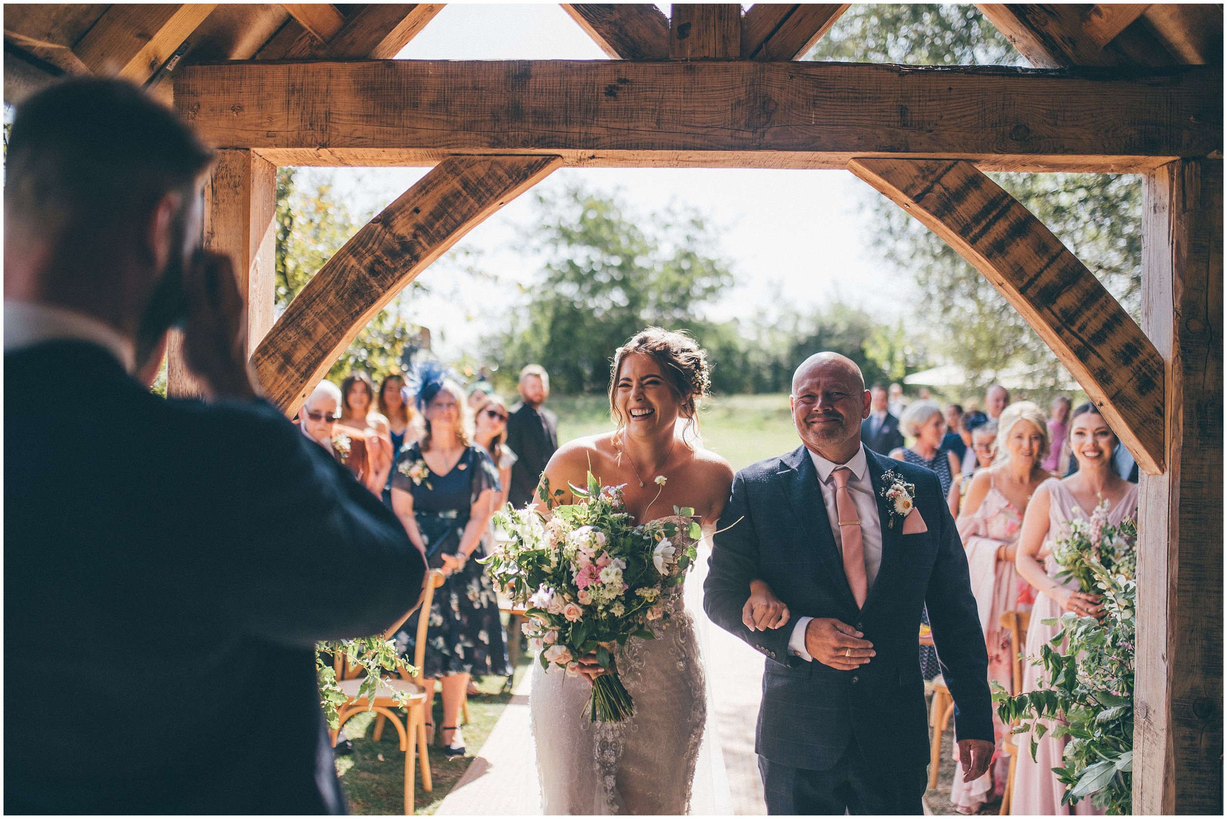 Bride smiles at her husband to be, walking down the aisle with her Dad at Skipbridge Country Wedding venue in Yorkshire