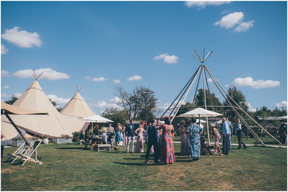 Wedding guests outside at the tipi reception on a sunny day at Skipbridge Country Wedding venue in Yorkshire