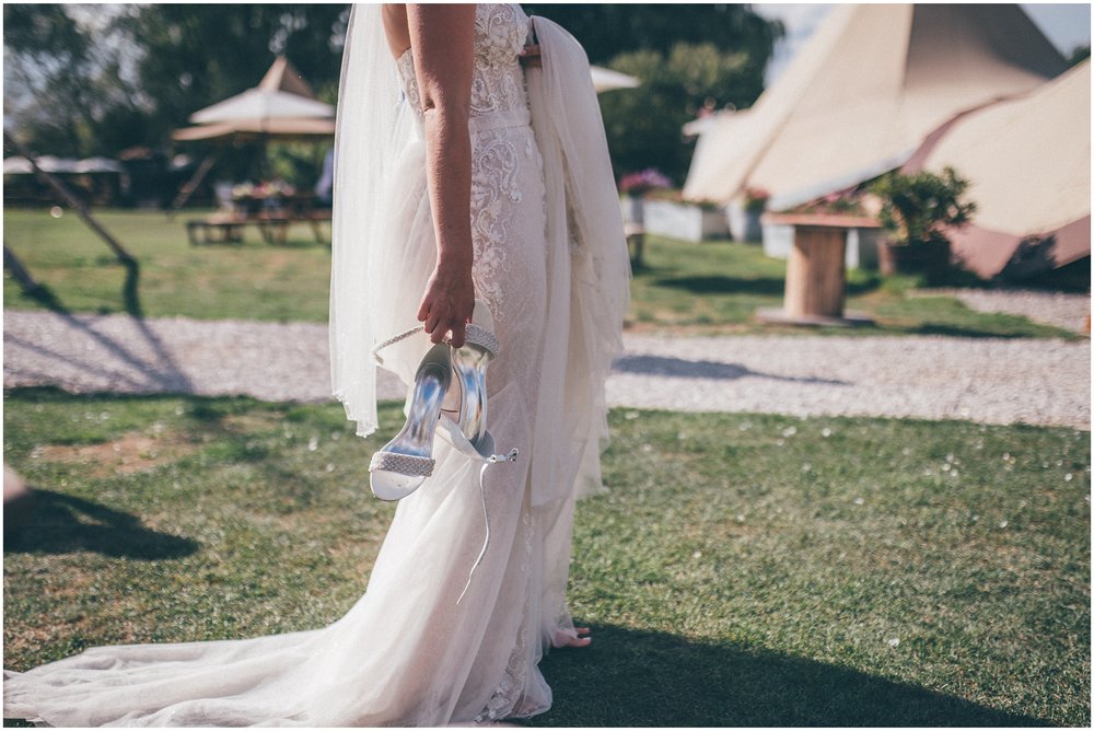 Bride carries her wedding shoes at a summer wedding at Skipbridge Country wedding venue in Yorkshire