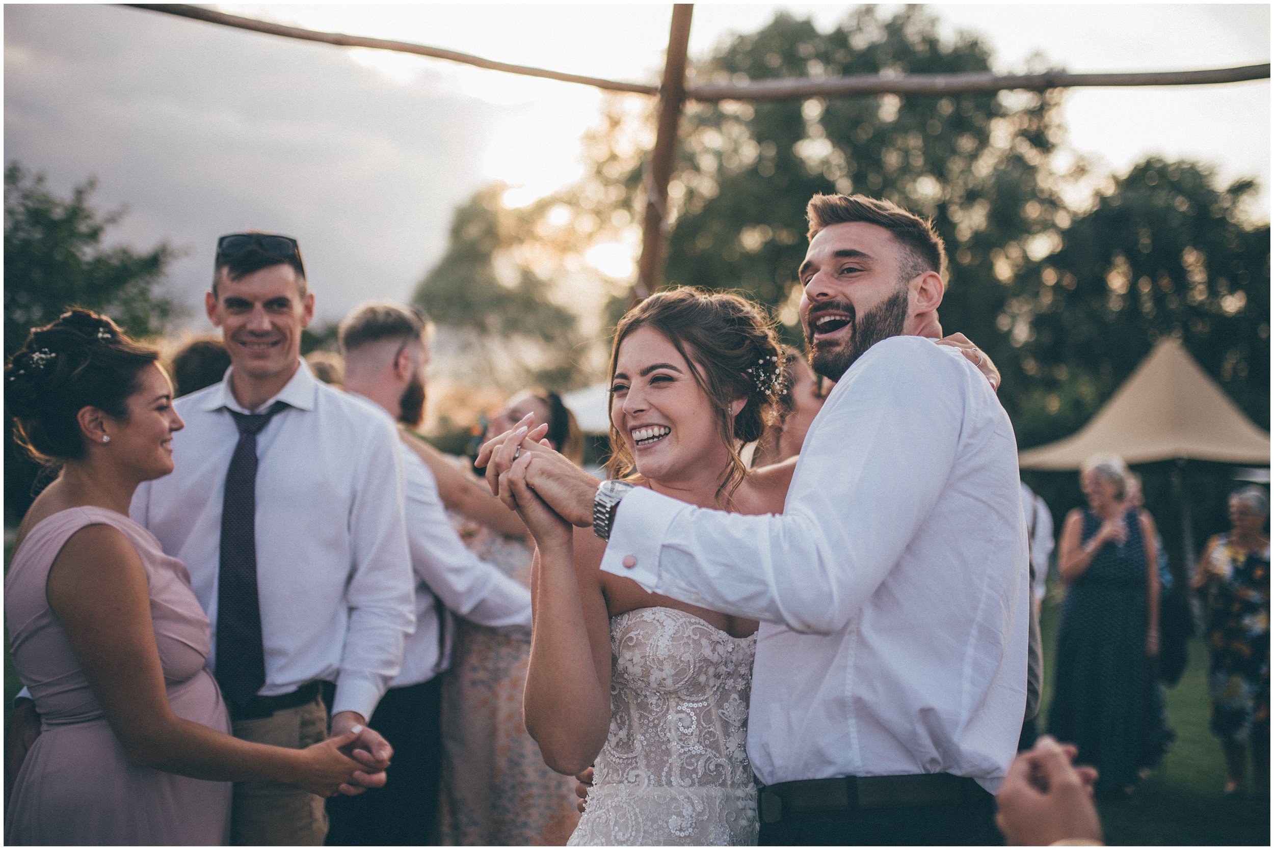 Wedding guests join the bride and groom and dance outside in the sun at Skipbridge Country wedding venue in Yorkshire