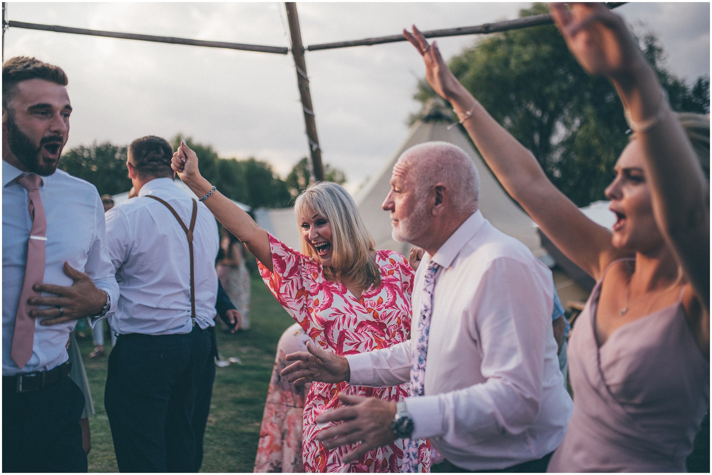 Wedding guests join the bride and groom and dance outside in the sun at Skipbridge Country wedding venue in Yorkshire