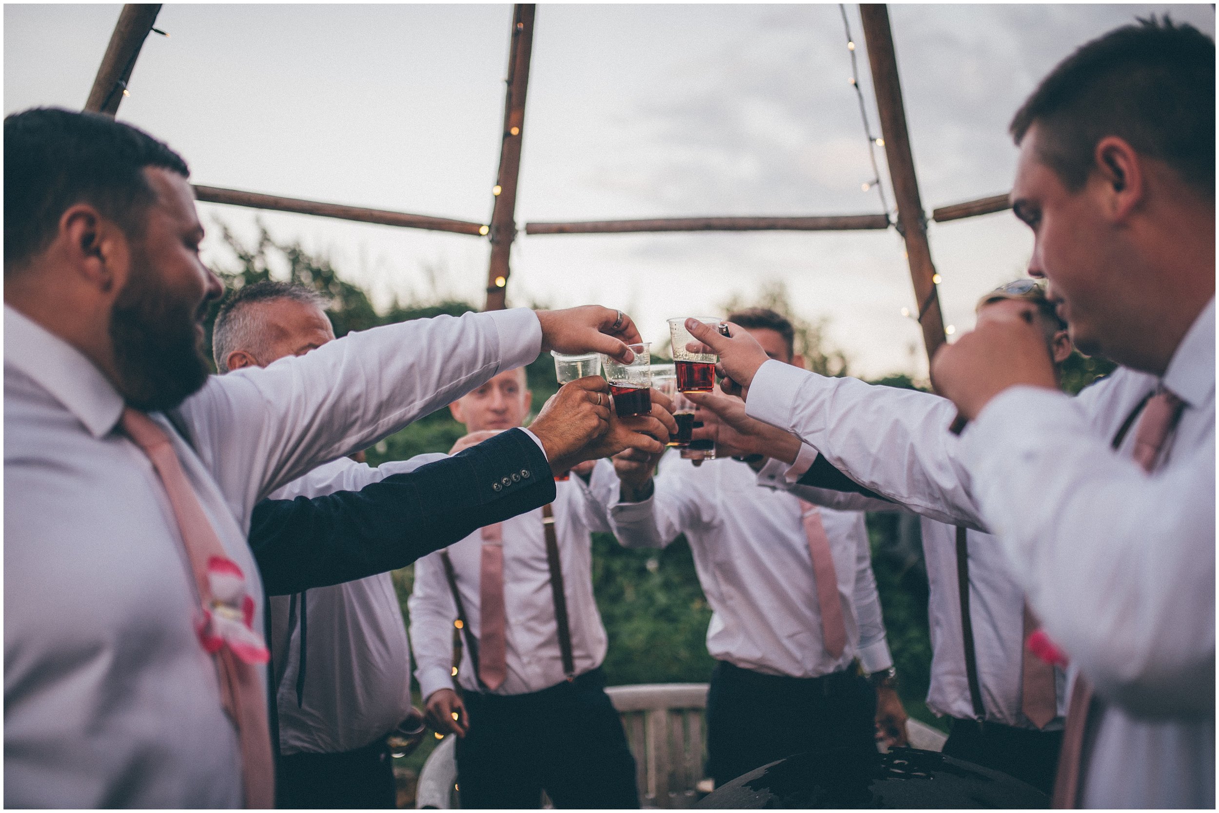 Groom and his friends have cigars and shots at the summer wedding at Skipbridge Country Wedding venue in Yorkshire