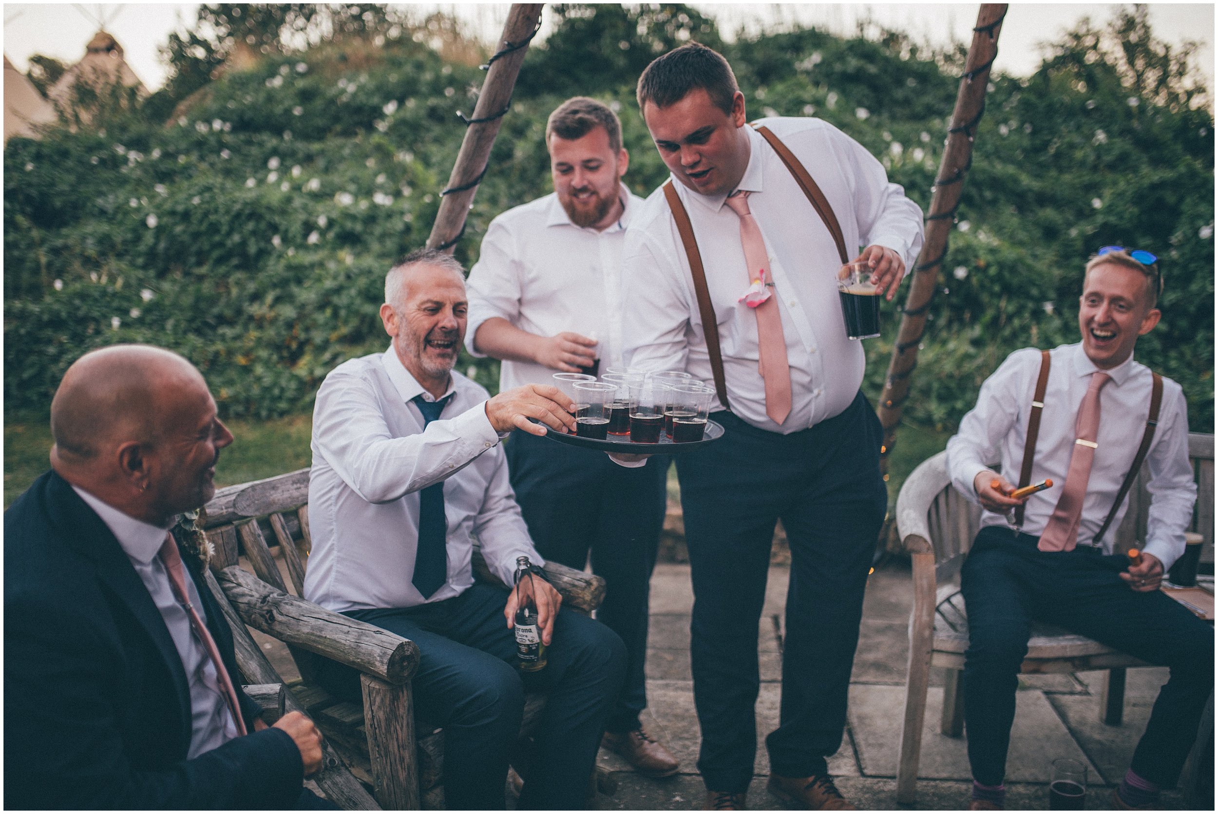 Groom and his friends have cigars and shots at the summer wedding at Skipbridge Country Wedding venue in Yorkshire