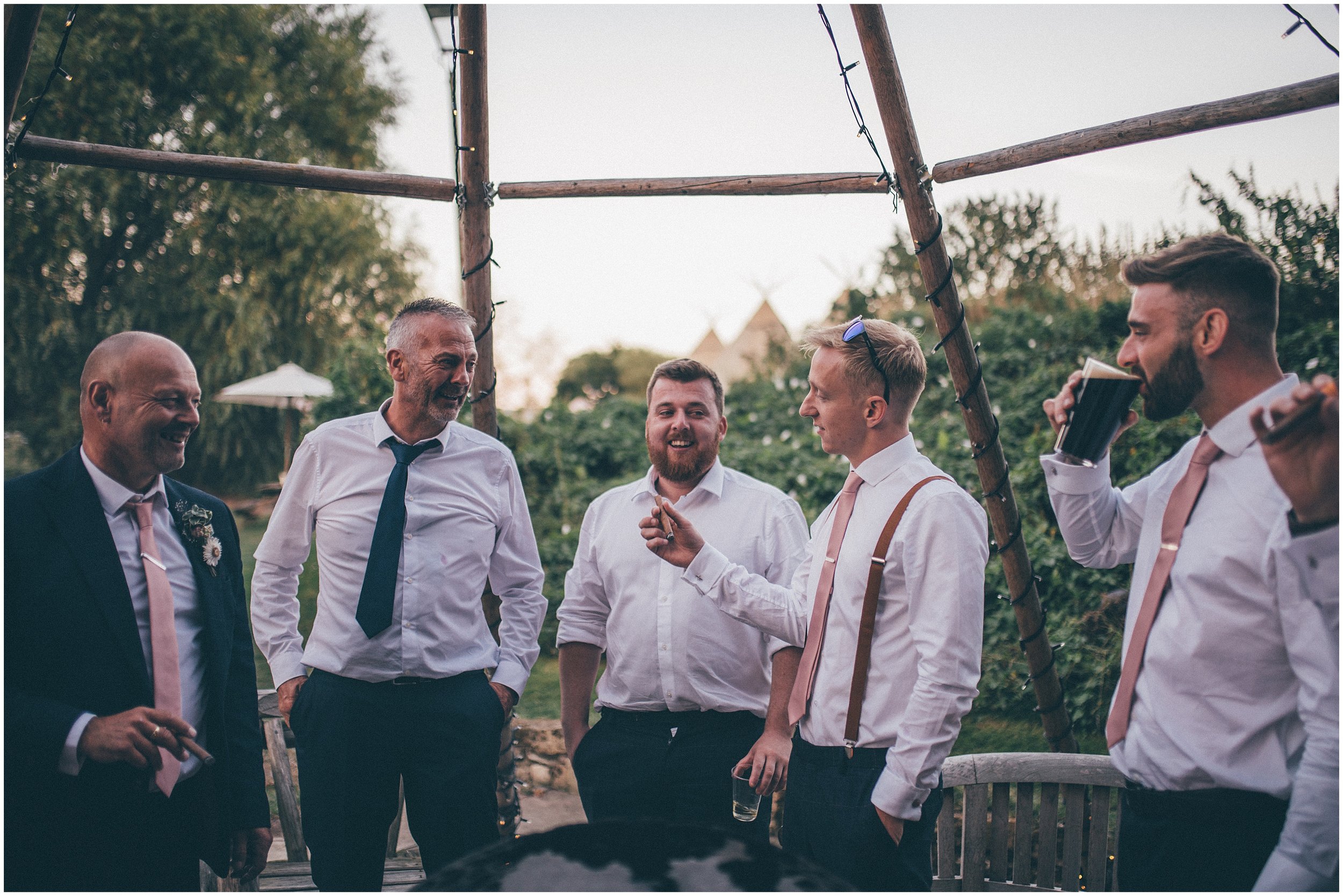 Groom and his friends have cigars and shots at the summer wedding at Skipbridge Country Wedding venue in Yorkshire