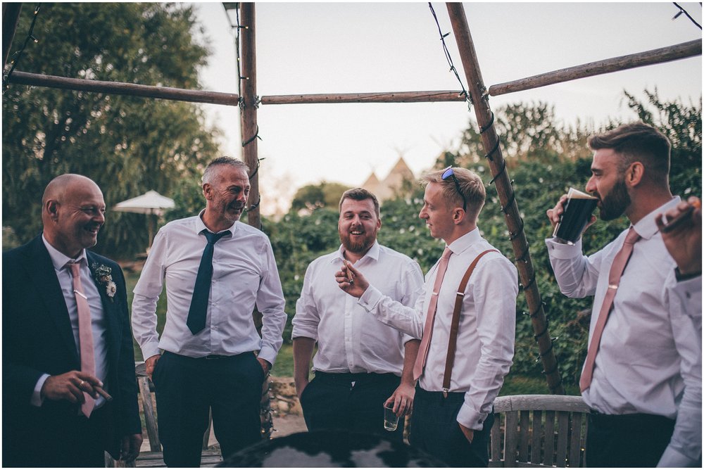 Groom and his friends have cigars and shots at the summer wedding at Skipbridge Country Wedding venue in Yorkshire