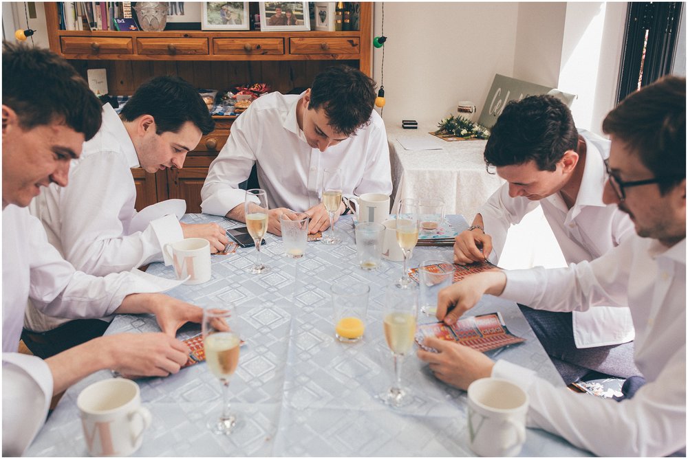 Groom and his groomsmen using scratch cards before the summer wedding at Sefton Palm House in Liverpool