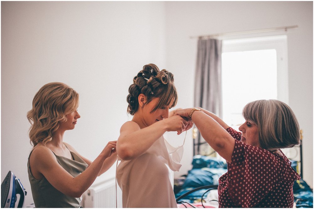 Bride's mum and sister help her into her Grace Loves Lace wedding dress