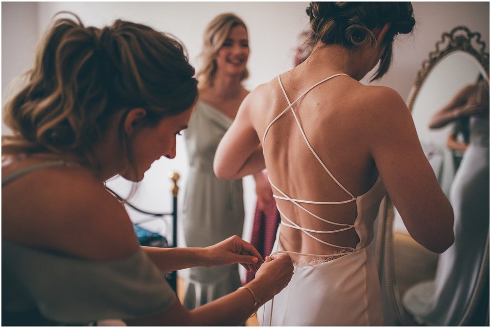 Bride's sister ties her into her Grace Loves Lace wedding dress