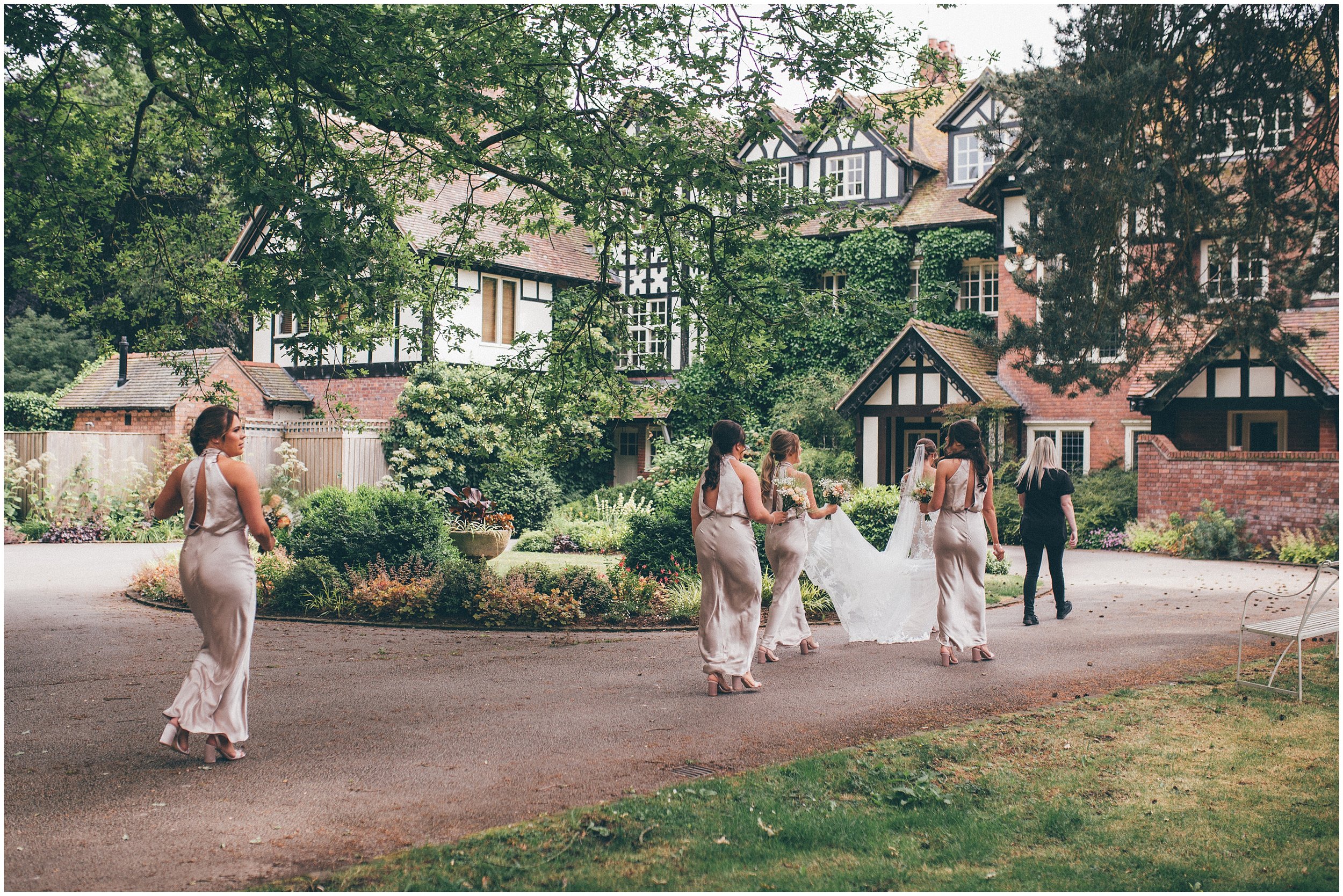 Bride and bridesmaids walk through house at Abbeywood Estate wedding venue in Delamere, Cheshire