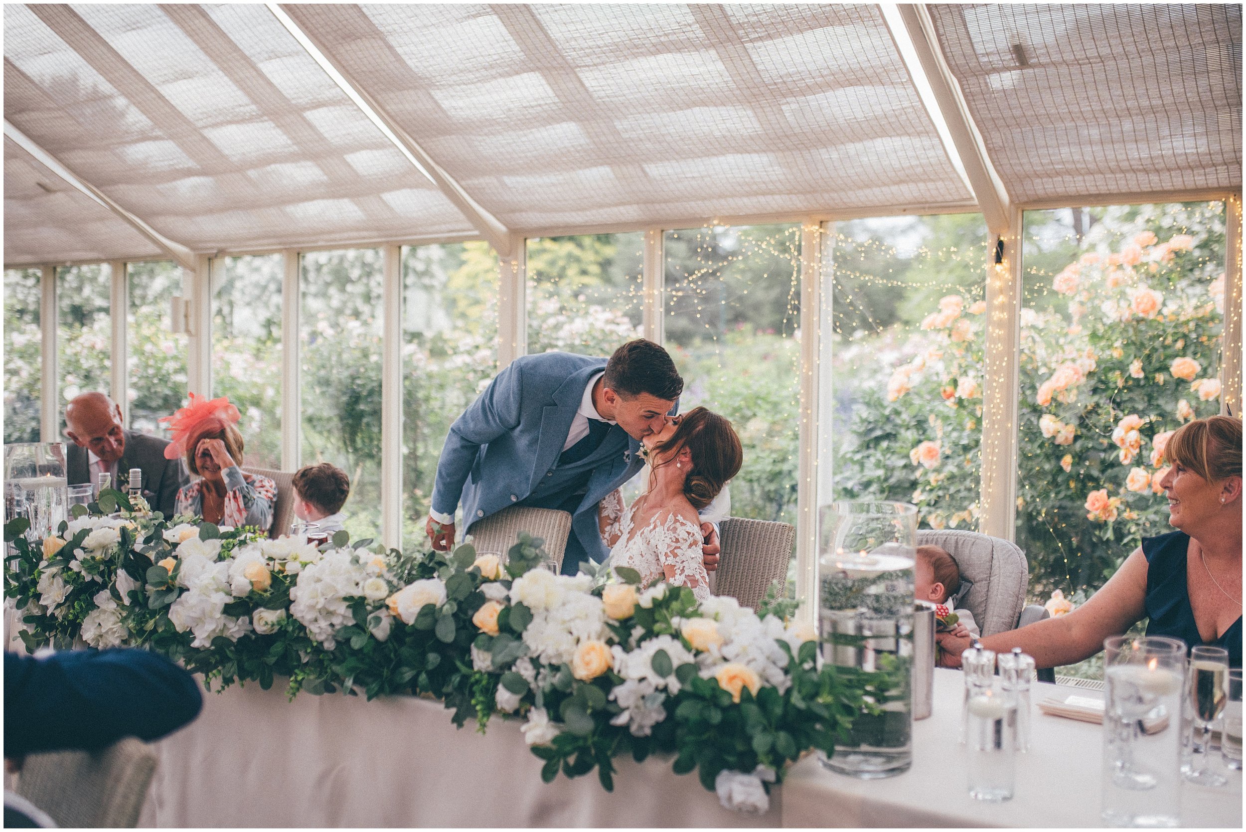 Bride and groom and guests enjoy speeches in the conservatory at Abbeywood Estate in Delamere, Cheshire.