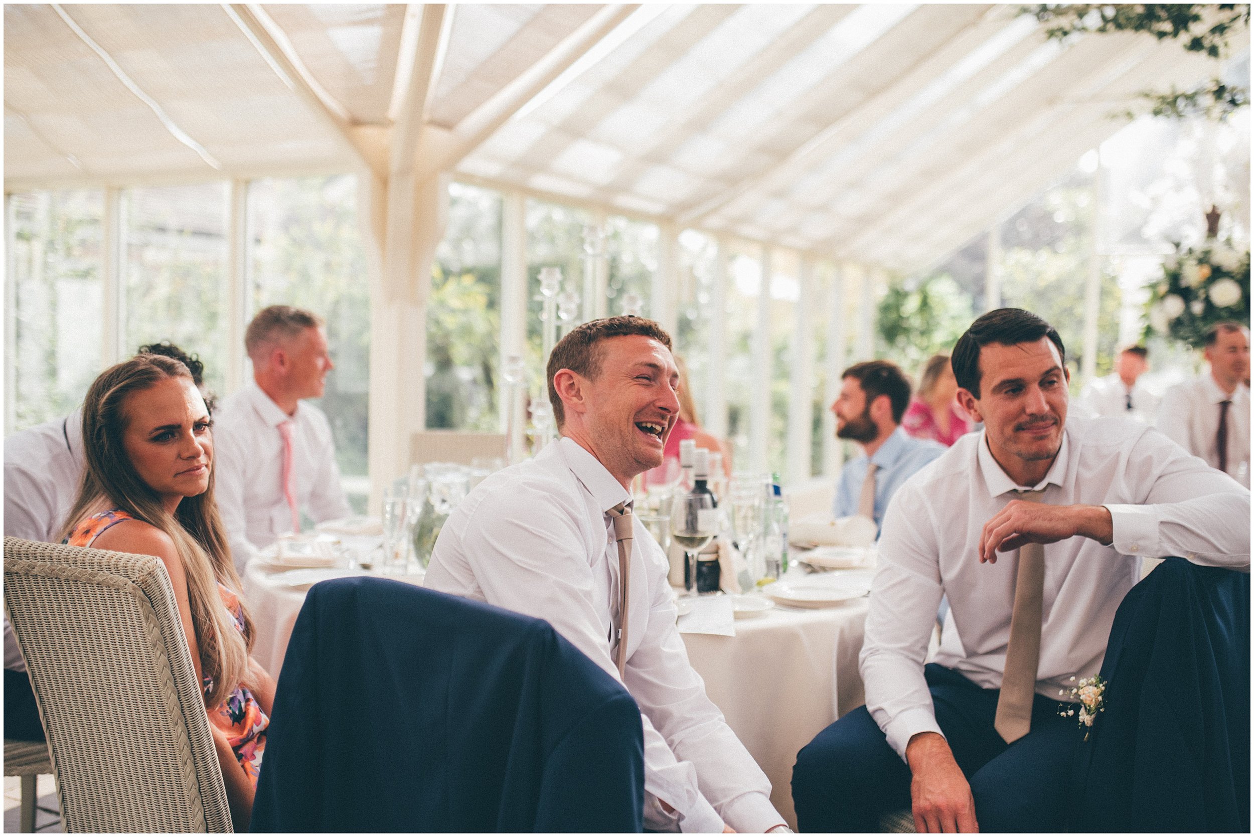 Bride and groom and guests enjoy speeches in the conservatory at Abbeywood Estate in Delamere, Cheshire.