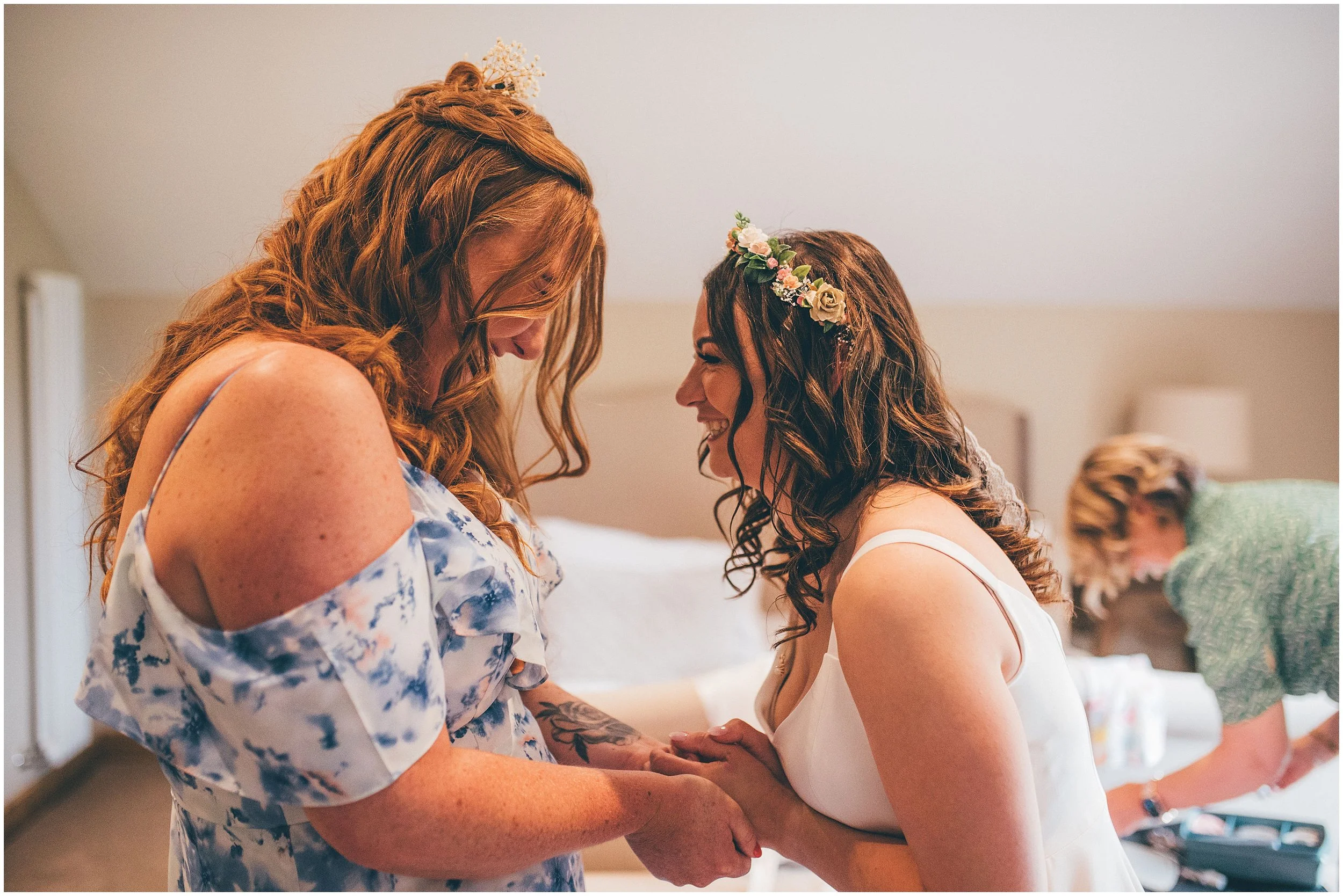 Bride and her maid of honour giggle whilst they both get ready in the Bridal Suite at Hobbit Hill wedding venue in Clitheroe