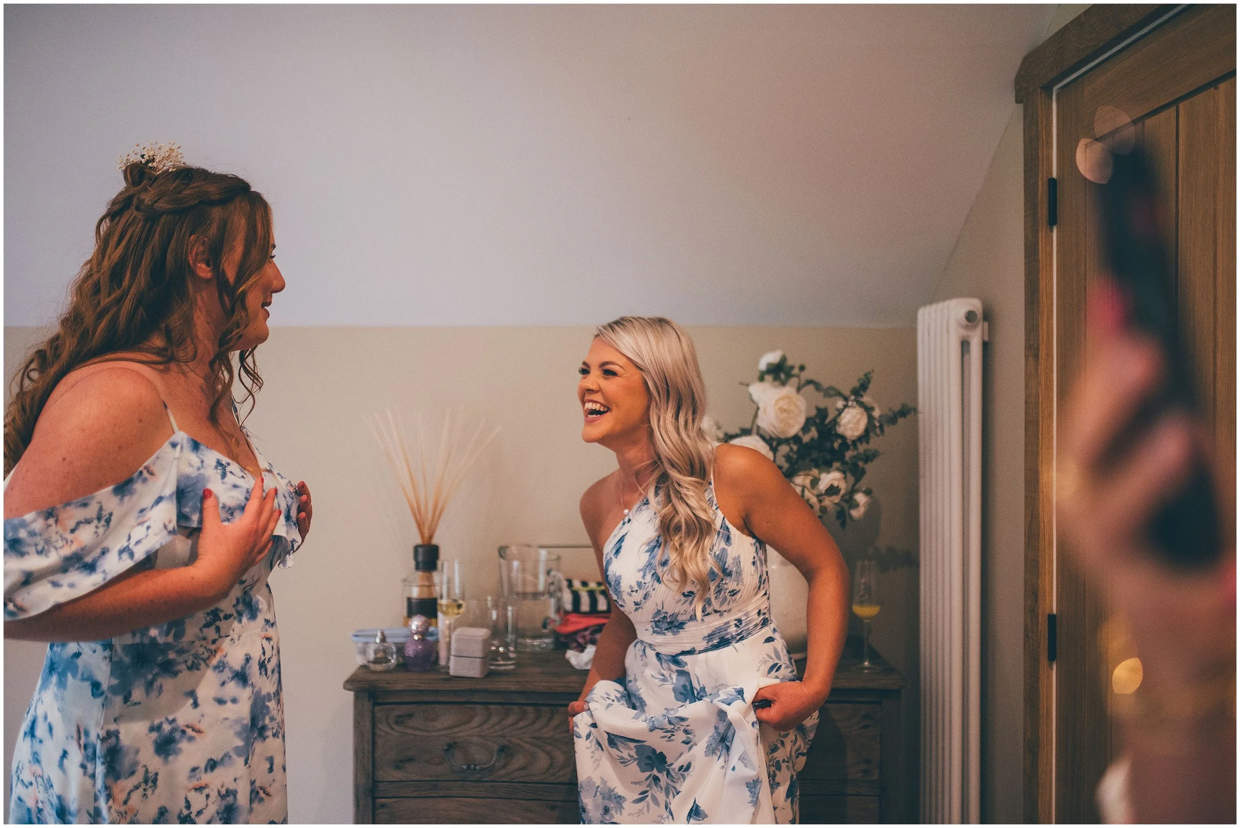 Bridesmaids laugh happily in the bridal suite at Hobbit Hill wedding venue in Clitheroe, Lancashire.