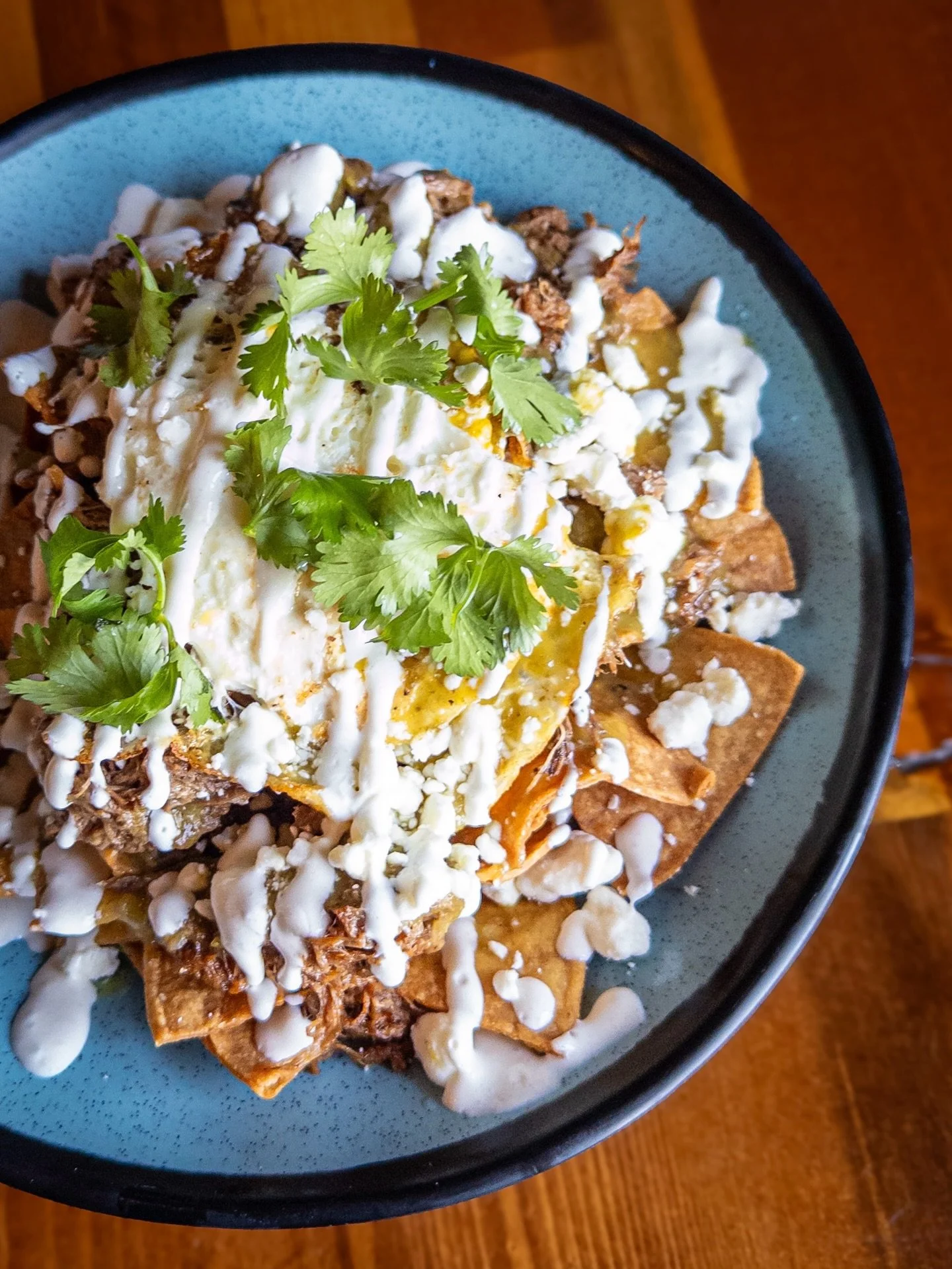 GREEN CHILAQUILES WITH BIRRIA
corn tortilla chips topped green chile sauce, beef birria, fried egg, red onion, crema, and goat cheese crumbles. 
Pair with GROWL K&Ouml;LSCH, available on draft and in 16oz cans to-go. 

Green Chilaquiles available dur