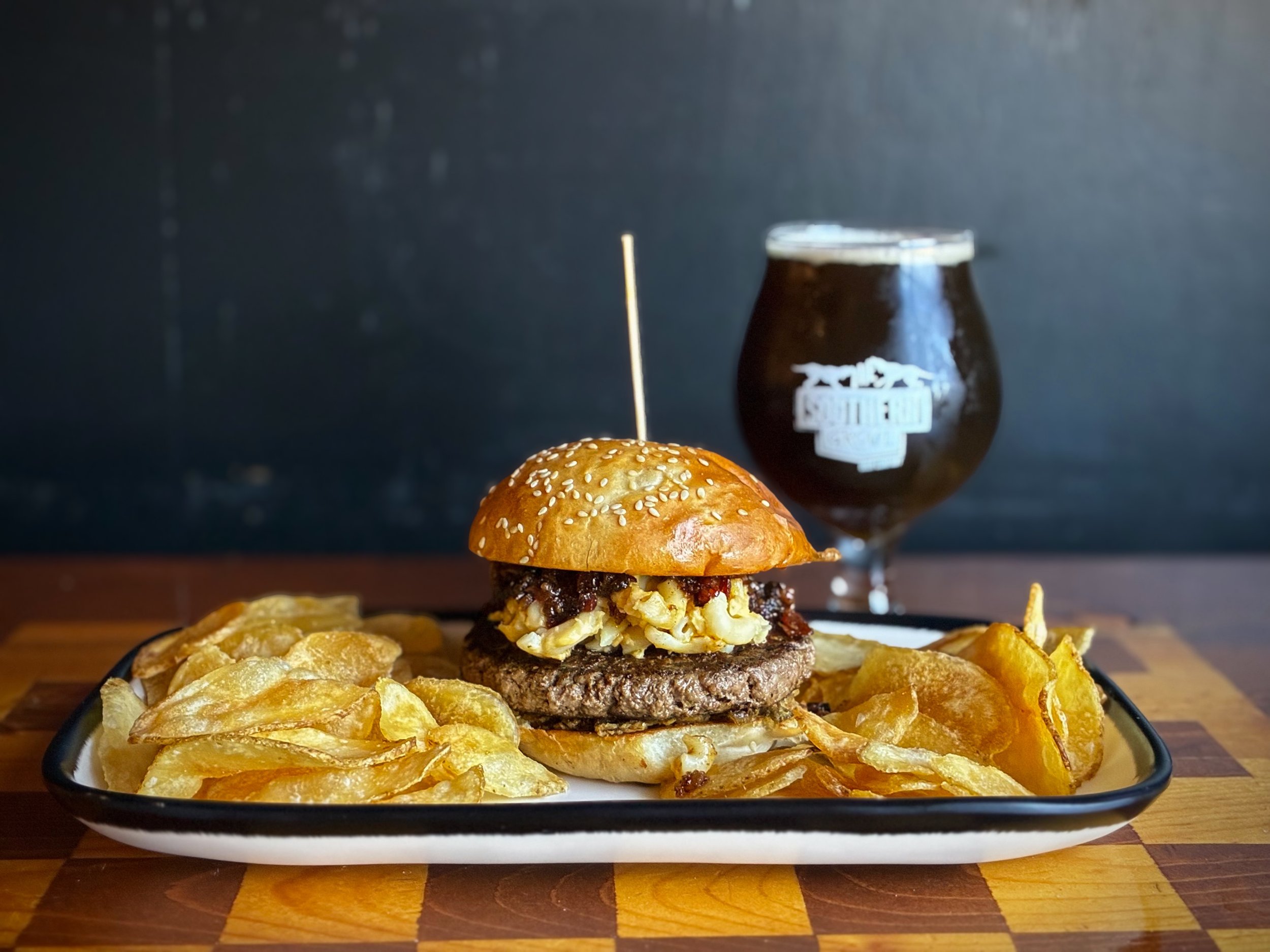A TALE OF FOUR CHEESES BURGER topped with four cheese Mac &amp; cheese, jalape&ntilde;o bacon jam, crumbled pork rinds, and crispy jalape&ntilde;os on a house sesame bun. 
Available during lunch, dinner, and brunch through Sunday. 
Pair with SOCIAL L