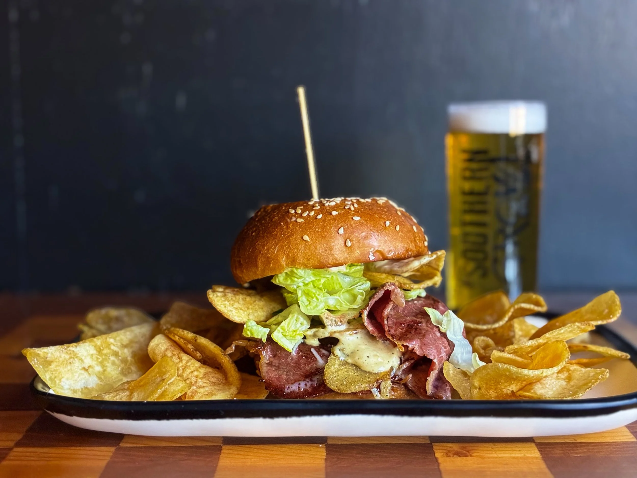 CAESAR CORNED BEEF SANDWICH 
Corned beef, Asiago cheese, Caesar spread, spicy Italian chips, and romaine lettuce on a house sesame bun. 
Weekly sandwich special available through Sunday during lunch, dinner, and brunch. 
Pair with GROWL K&Ouml;LSCH a