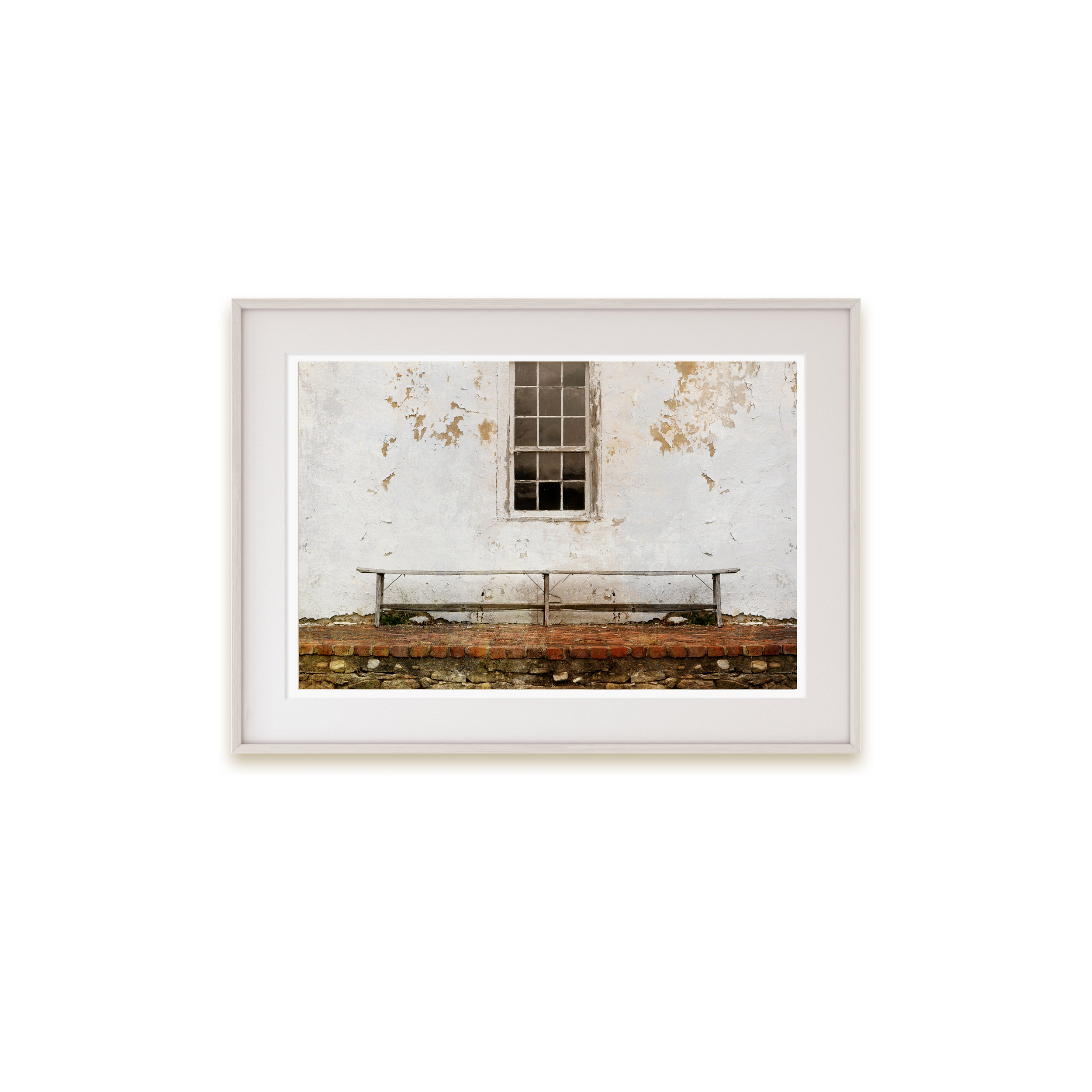 A color print of a wooden bench print set against a peeling old building