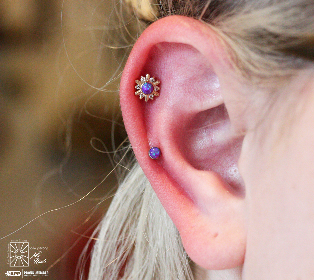 Two fresh helix piercings Mic got to do yesterday, featuring a gorgeous Yellow Gold “Snowflake” with clear cz’s and a synthetic Purple Opal center from Le Roi Fine Jewelry and a coordinating Purple Opal set in titanium from NeoMetal. Such a fun pairing!