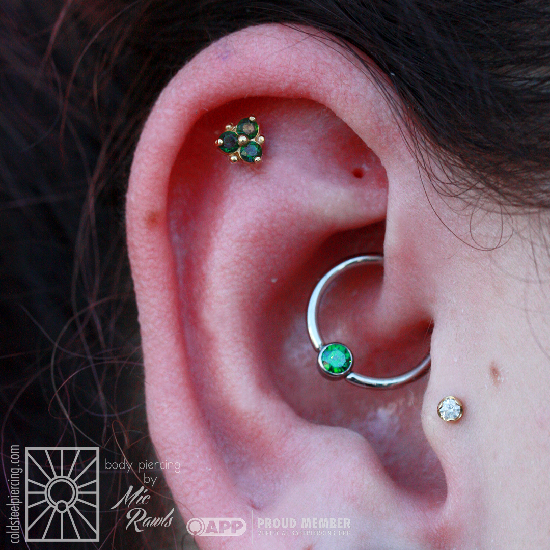 There will always be a special place in our hearts for coordinated jewelry sets, and this helix/daith duo is no exception! The beautiful yellow gold and Rainforest Topaz "Triplet" from Scylla Fine Jewelry is complimented wonderfully with a rich green cz captive gem from Industrial Strength.