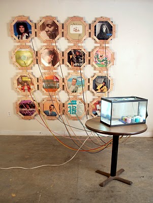 Color Pump record album covers, vinyl tubing, suction cups, superglue, acrylic paint, table, aquarium, pebbles, air pump, light, water, baby food jars, wood dimensions variable 2011 Paint matched to colors on record album covers connects the album covers to reservoirs housed inside of a bubbling aquarium.