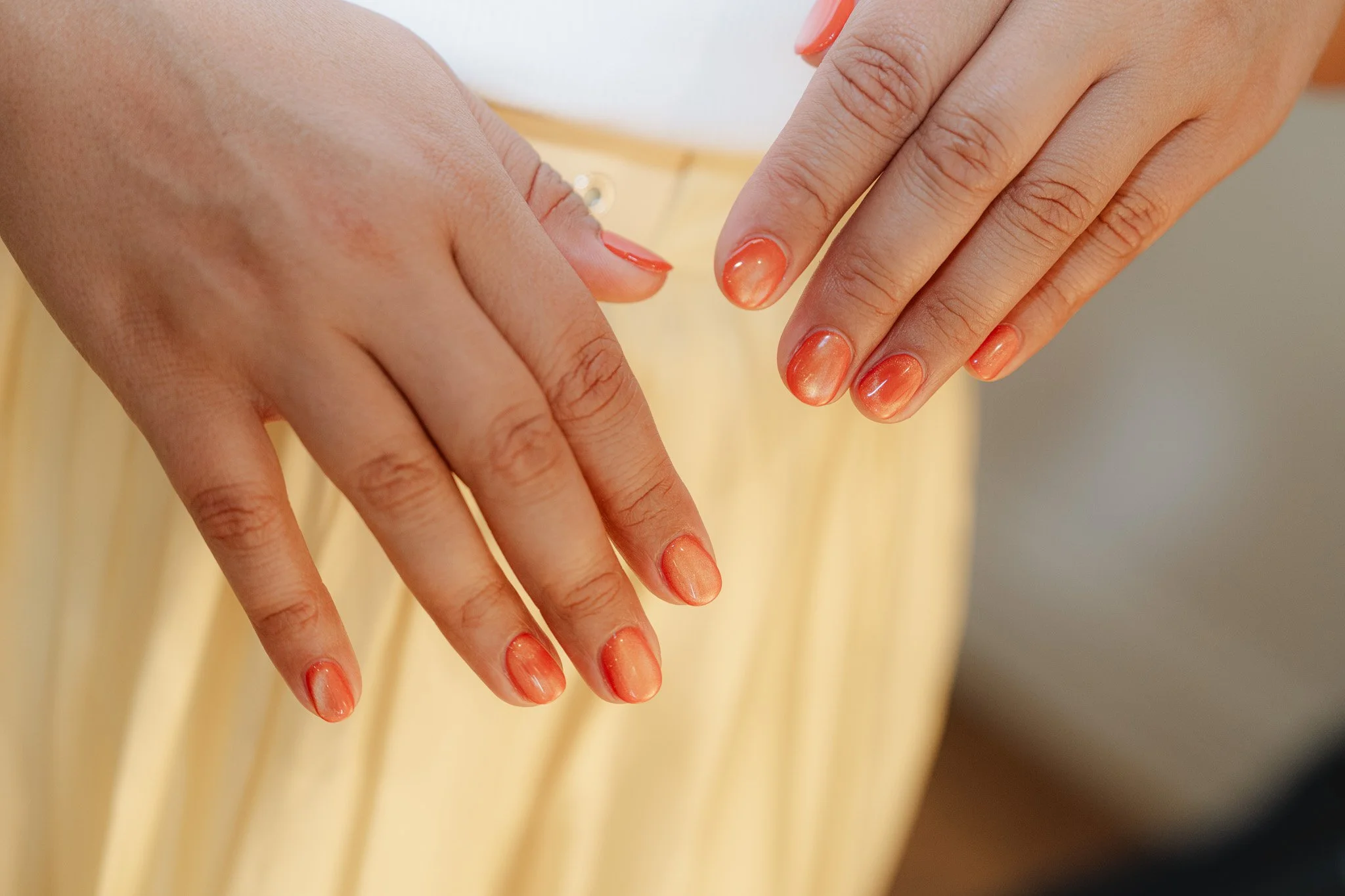Close-up of hands with manicured nails painted in shades of orange and beige.