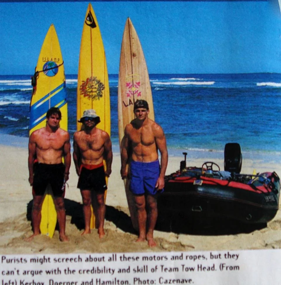Tow surfing and all its tributaries leads back to Buzzy and Laird Hamilton standing on the beach at Backyards, with one finger in their ears and one in their exhaust manifolds, with the wrong boat, the wrong boards and the wrong engine. They gradually got an act, and changed big wave surfing forever. This is Laird and Buzzy with Darrick Doerner making three.