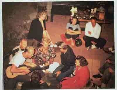 Pete Peterson a la guitarra, Dave Rochlen al ukelele y una guapa bobby soxer llamada Norma Jean Baker con una chaqueta sobre los hombros.  Fiesta en la playa de Los Ángeles, alrededor de 1947. Fotógrafo desconocido.