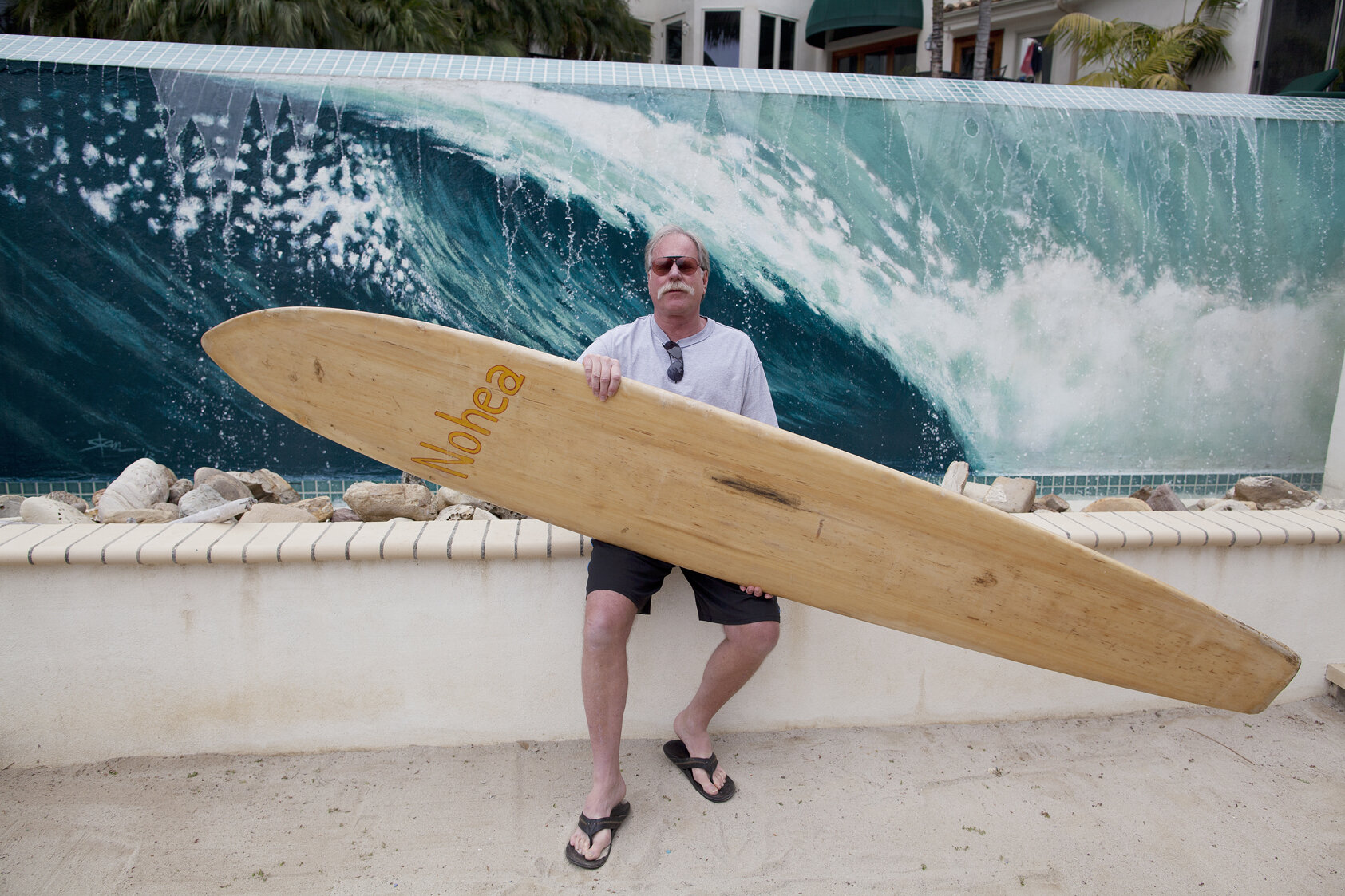  Griff with one of his collectible surfboards in front of his pool. 