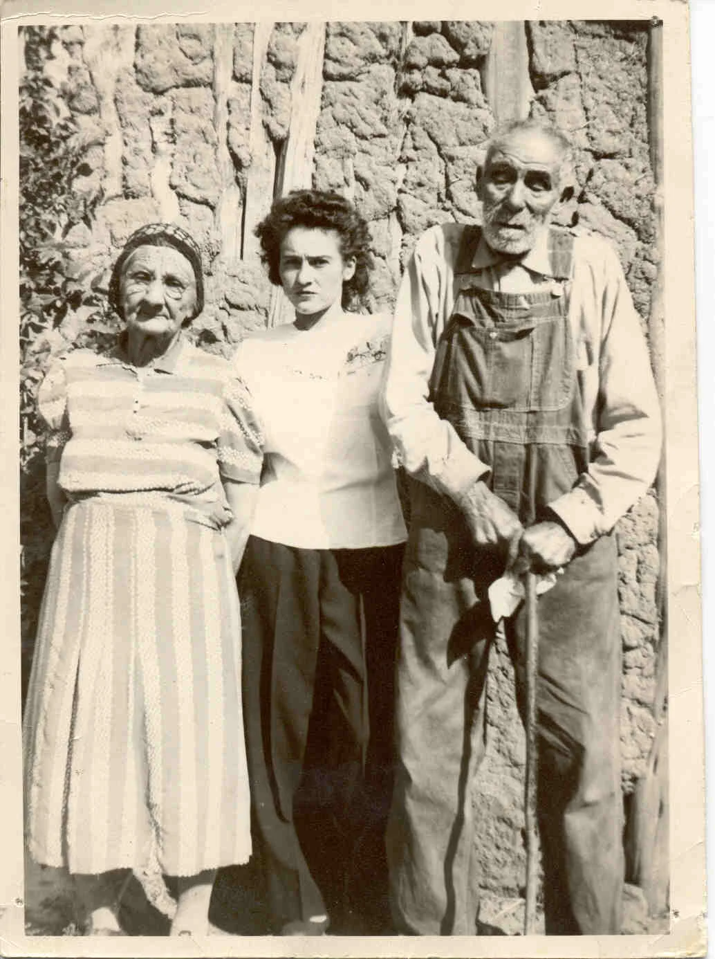 Great Grand Aguelo, Great Grand Vava, and aunt standing in front of a house built of traditional posts and adobe