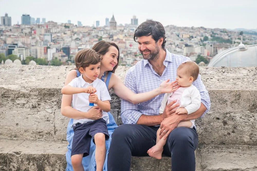 A dad, a mom & their 2 kids sitting near the Süleymaniye mosque during a family photo session