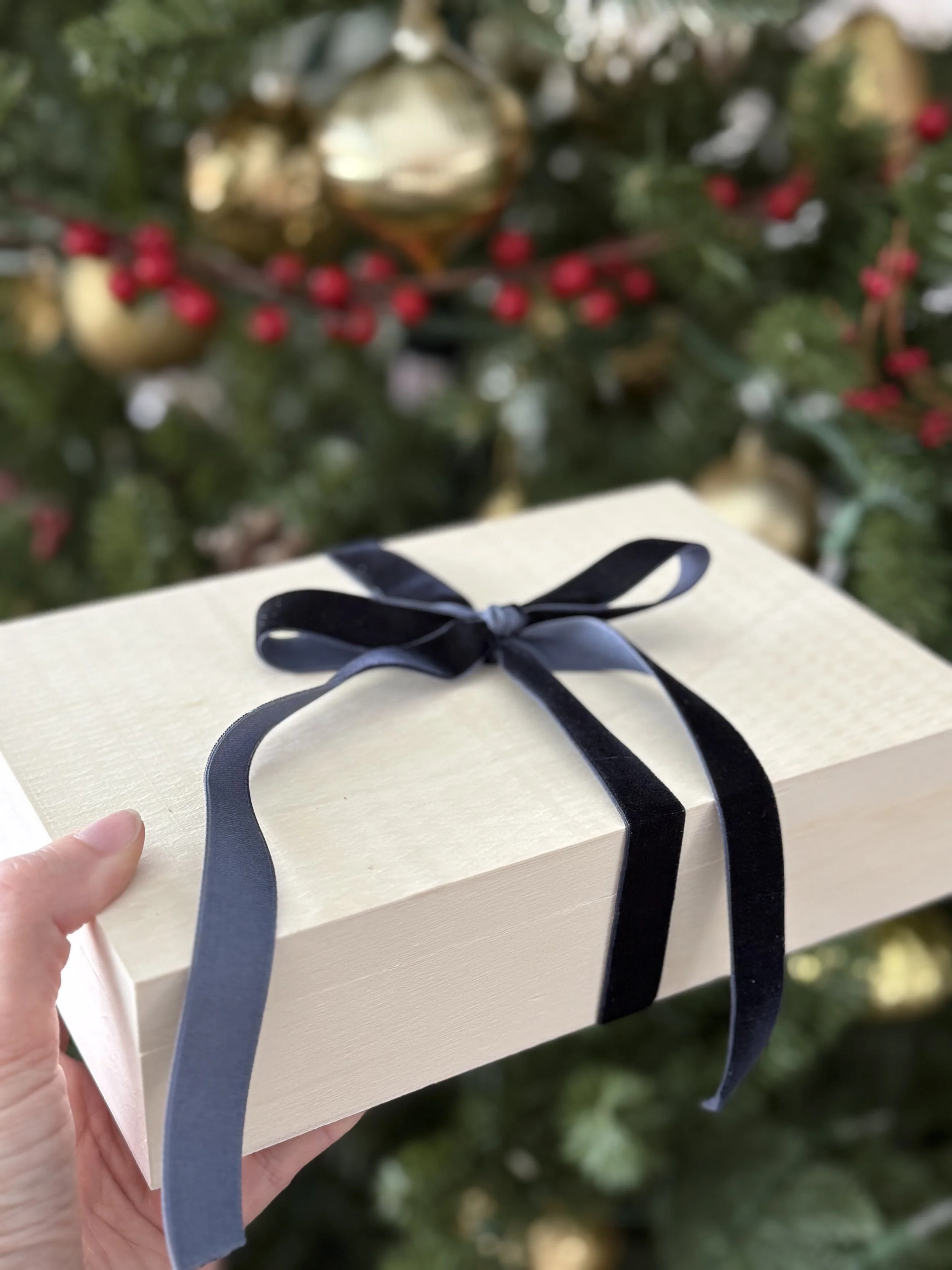 Portrait gift certificate box with Christmas decor in the background.
