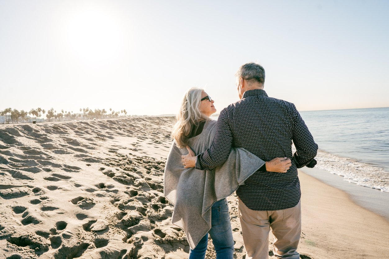 Couple walking on the beach with arms around eachother