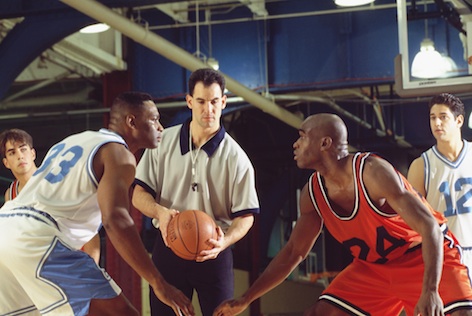 A referee is in control of the game. At times he throws the ball straight up in the air and players jump for it. It's called a tip off. ©iStock