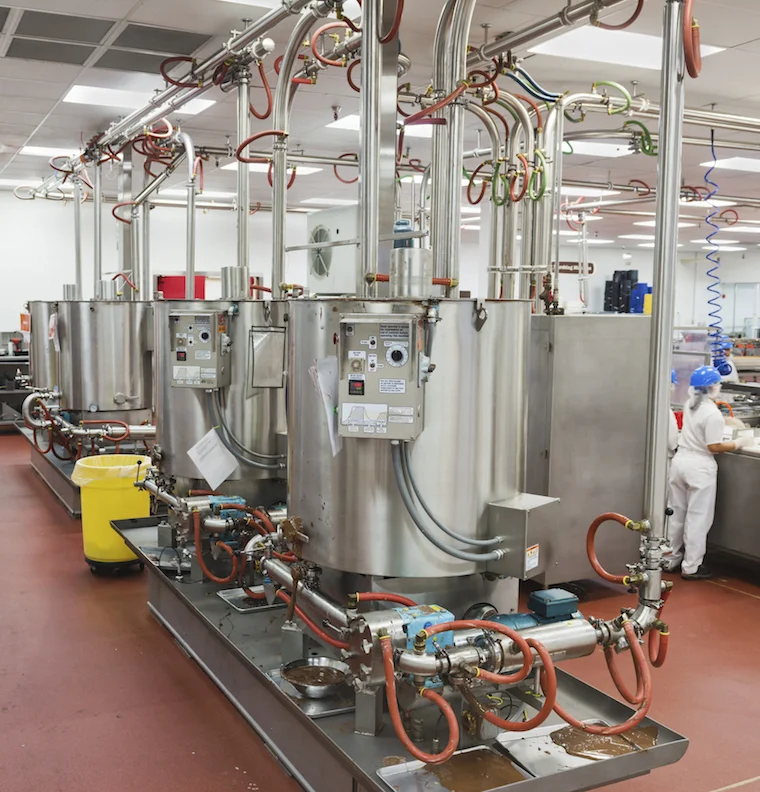 Chocolate is stirred in large vats in a chocolate factory. ©iStock