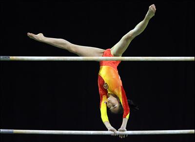 A gymnast swings and twists on the uneven bars