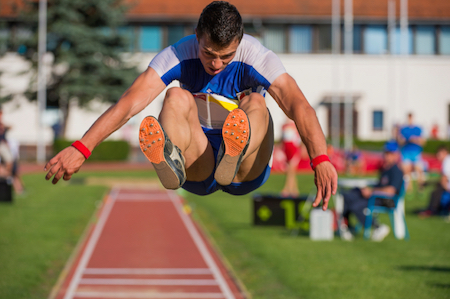Athletes run and take off from the take-off board, landing in the sand pit. © Getty Images