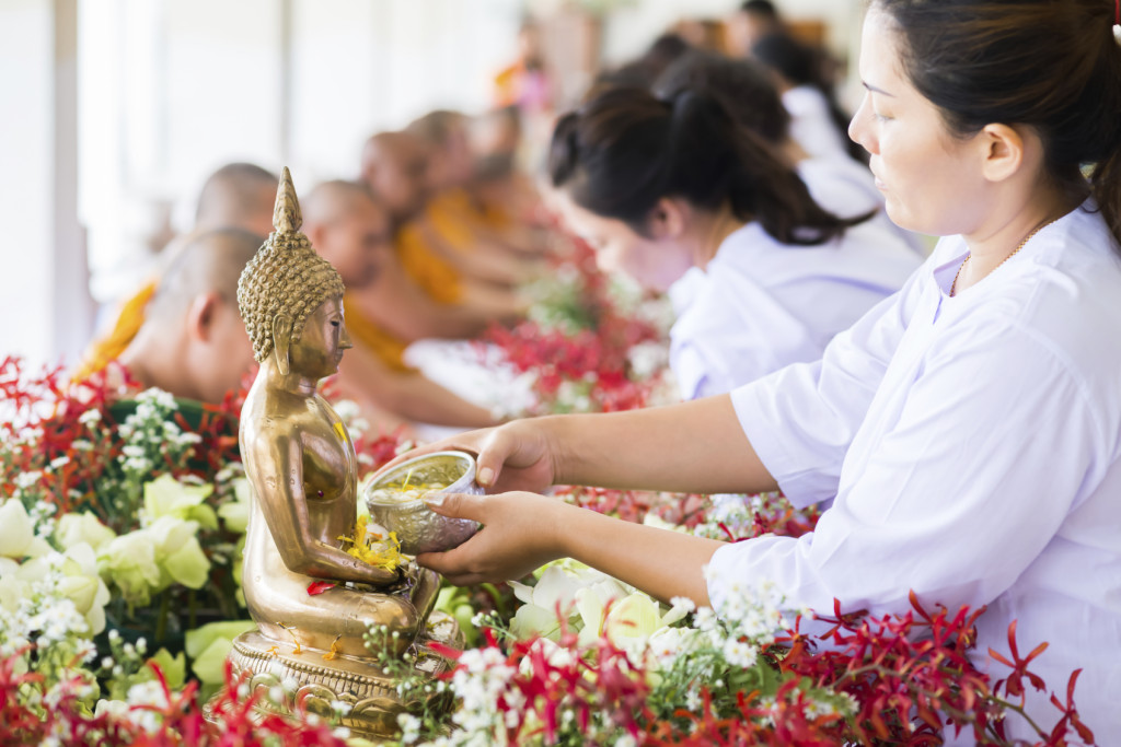 People offer flowers to a statue of the Buddha © iStock