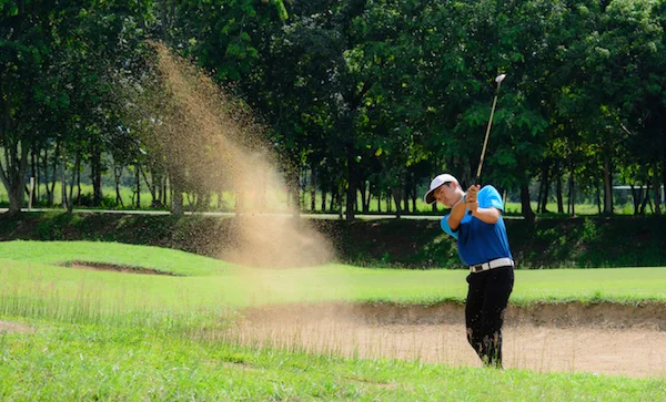 The golfer is trying to hit the ball out of the sand trap with as few strokes as possible. ©Getty