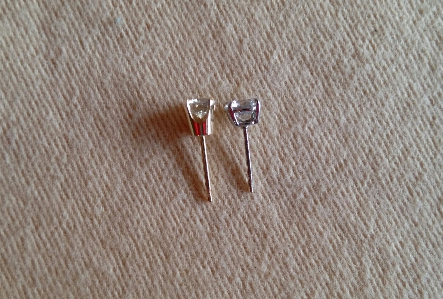 comparison of high vs low diamond mountings: the yellow gold earring on the left has a high base. The earring on the right is a low basket mounting.