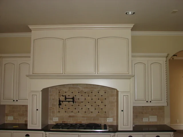  Custom vent cover with eyebrow arches and spice pullouts. Raised panel eyebrow arched doors with standard 1/2" overlay on the upper cabinets. Rope round corner moulding. 