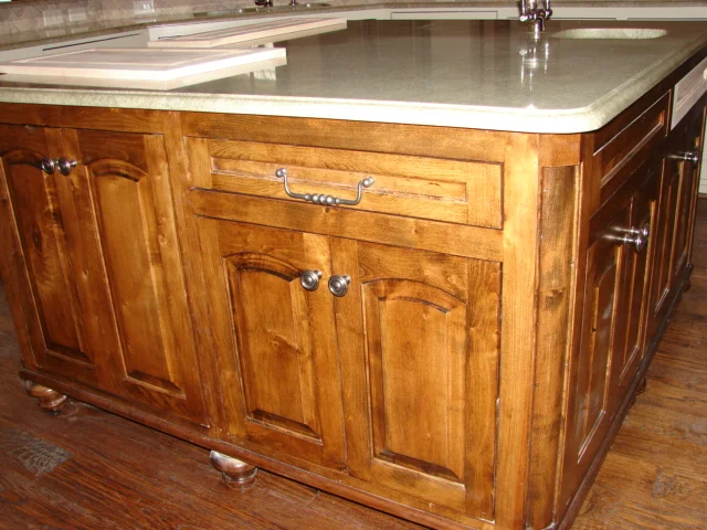  Knotty alder, inset, eyebrow arch raised panel doors, with classic round corner moulding and bun feet. 