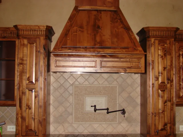  Knotty alder cabinets with raised panel eyebrow arched doors, round corners and dentil mould. 