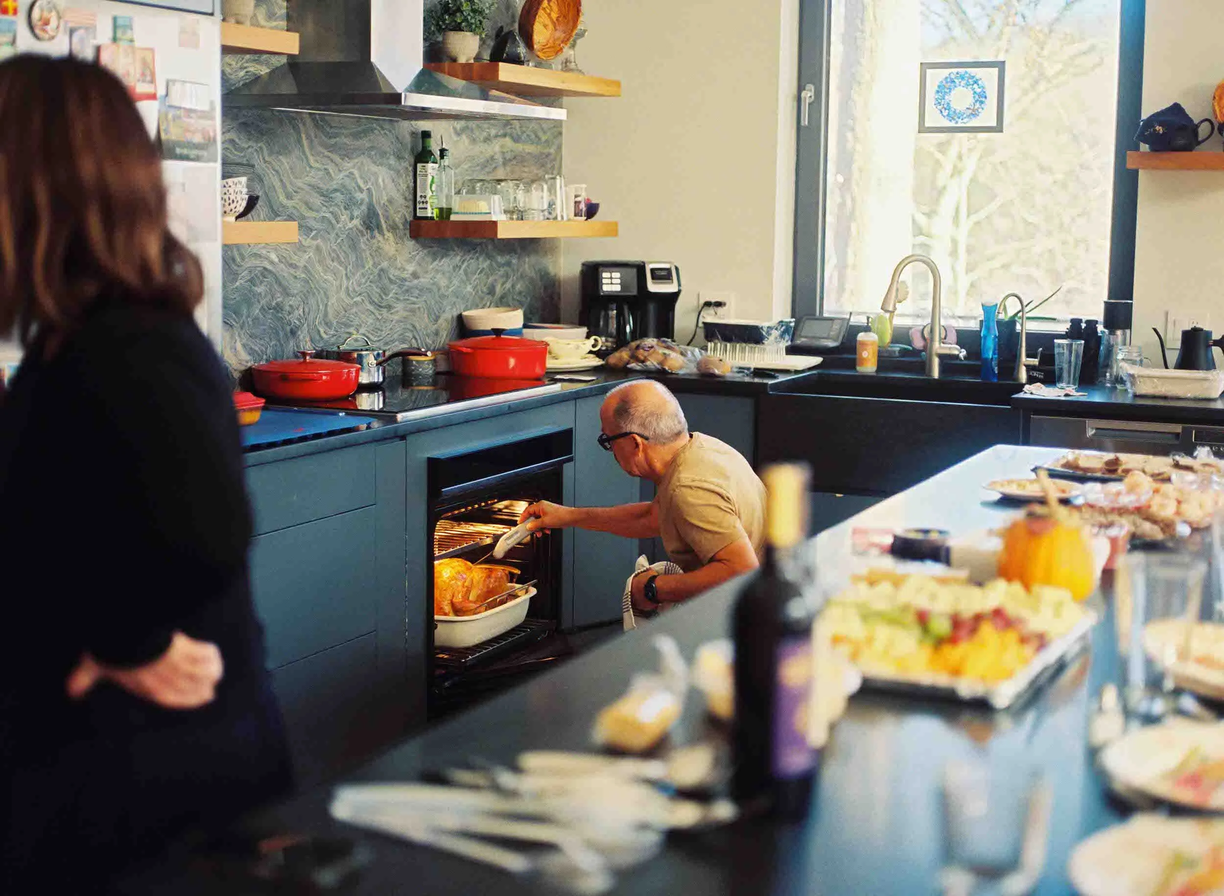 A person leaning down and checking on a turkey in an oven