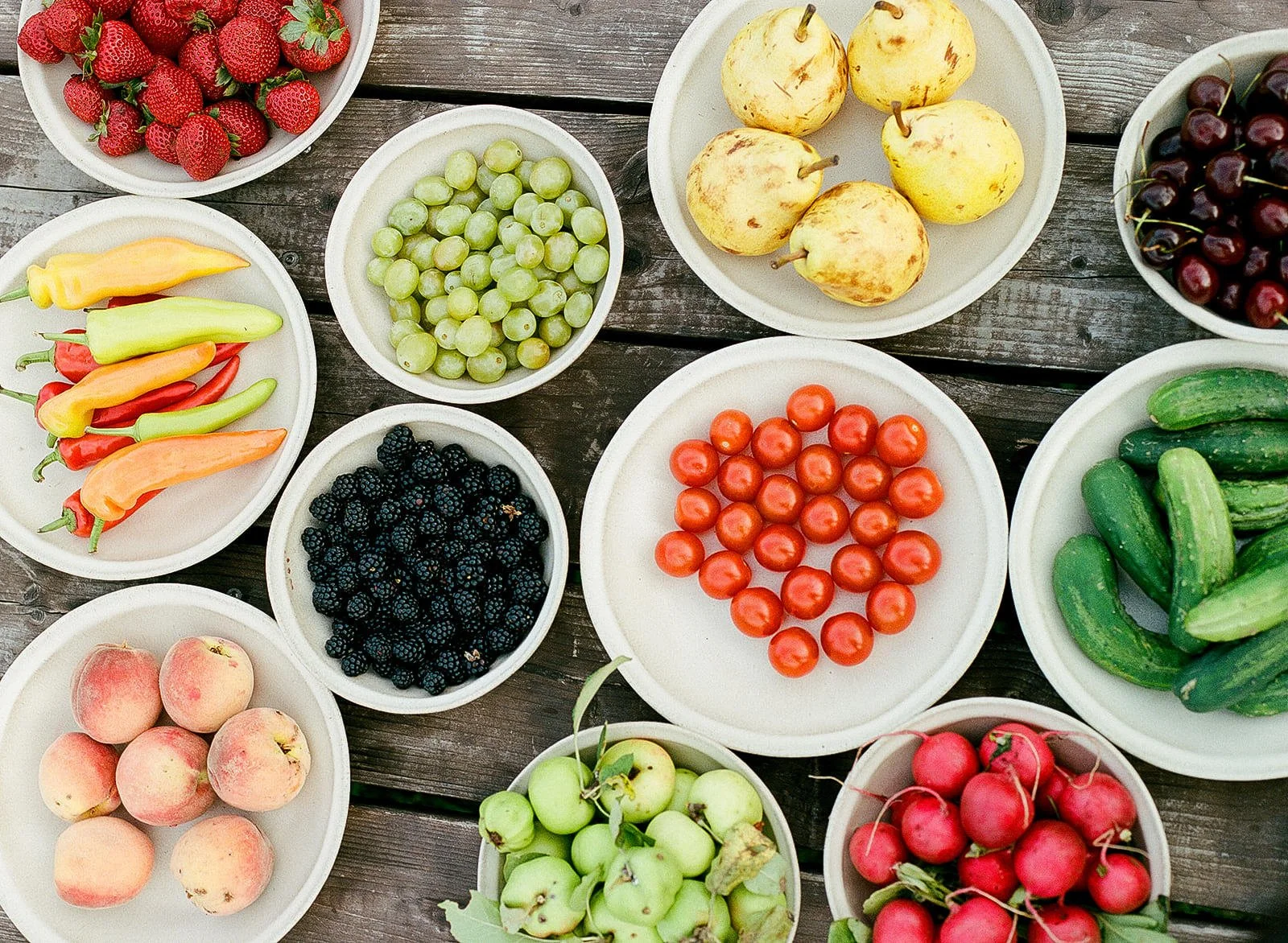 Various plates of fruits and vegetables laid out on a table