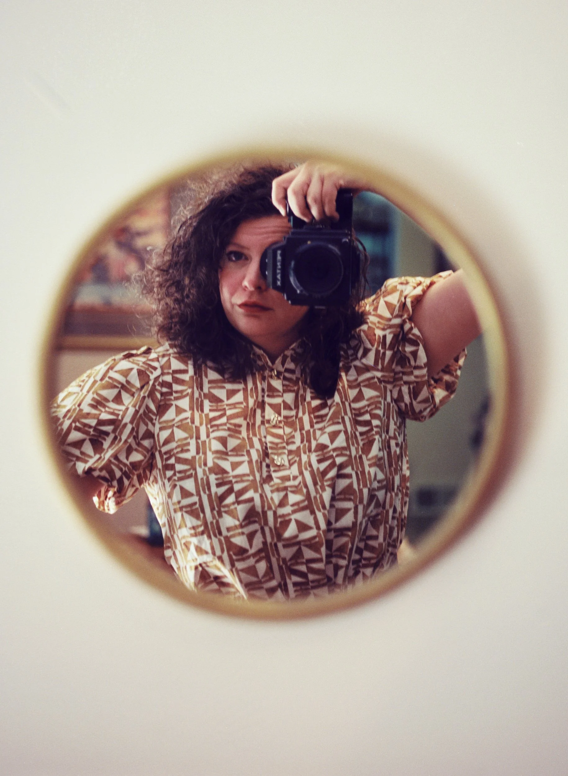 Mel taking a photo of herself in a round mirror
