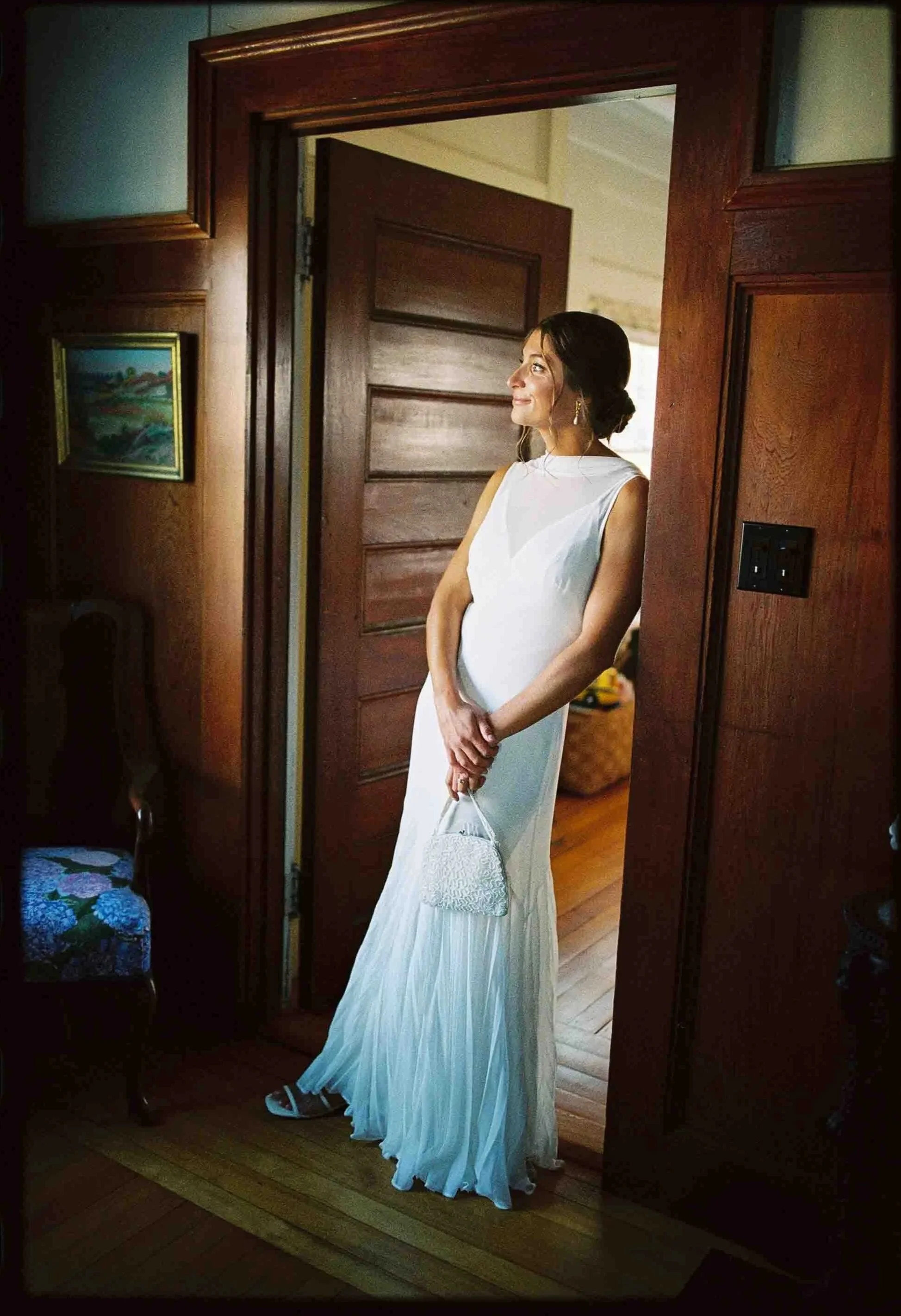 A newlywed in a wedding dress leaning against a doorframe